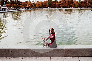 young woman and cute dog by the lake in an urban park. Love for animals concept. Retiro park Madrid