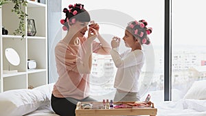 Young woman and cute girl take eye patches from cosmetic table.