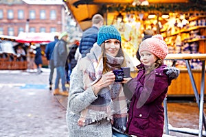 Young woman and cute kid girl with cup of steaming hot chocolate or children punch