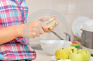 Young woman cuts apple on the kitchen