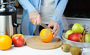 Young woman cuts an ripe orange for making fresh juice in the kitchen at home. Healthy food concept. Close-up