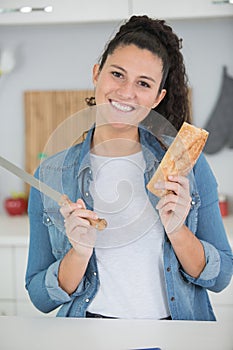 young woman cutting bread loaf in kitchen