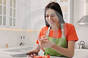 Young woman cutting finger with knife while cooking in kitchen