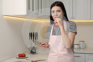 Young woman cutting finger with knife while cooking in kitchen