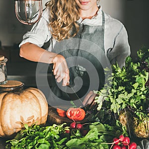 Young woman cutting herbs and vegetables for cooking, square crop