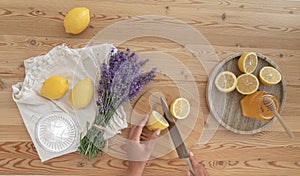 Young woman cutting lemon on wooden board. Preparation of fresh llemonade.