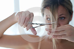 Young woman cutting off her bangs with scissors closeup