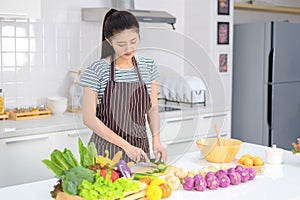 The young woman is cutting vegetables in the kitchen, cucumber slices that are sliced