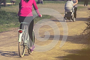 A young woman is cycling into the sunset in the park