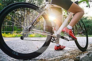 Young Woman Cyclist Riding Road Bicycle on the Free Road in the Forest at Hot Summer Day. Healthy Lifestyle Concept.