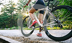 Young Woman Cyclist Riding Road Bicycle on the Free Road in the Forest at Hot Summer Day. Healthy Lifestyle Concept