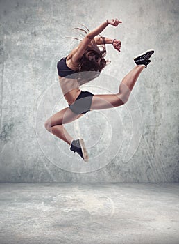 Young woman dancer with grunge wall background