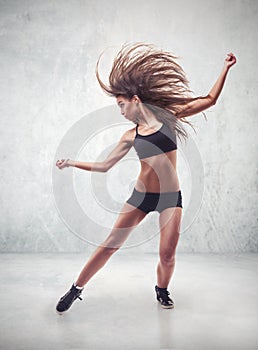 Young woman dancer with grunge wall background