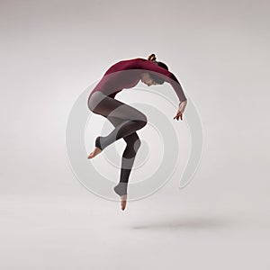 Young woman dancer in maroon swimsuit jumping