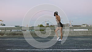 Young woman dances alone on empty street. Stylish and funky dancer performs freestyle in a deserted urban environment