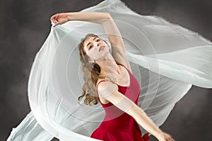 Young woman dancing with green fabric flying in the studio