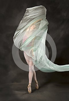 Young woman dancing with green fabric flying in the studio