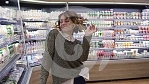 Young woman dancing through grocery store aisles. Excited woman having fun, dancing supermarket. Slow motion