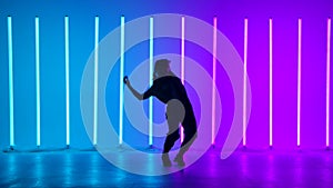 Young woman dancing street dance hip hop in a studio with neon lighting tube on a blue purple background. Hip hop dancer
