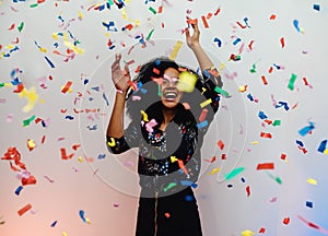 Young woman dancing under confetti at home