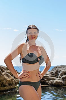 Young woman in dark-green swimsuit resting at the sea