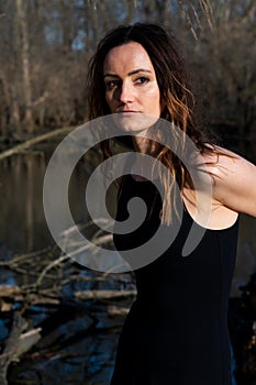 Young woman with dark long hair in black robes in the middle of the forest. Back to Nature concept