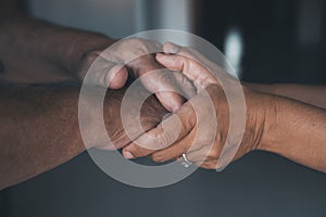 Young woman daughter granddaughter caregiver holding old senior female hand helping elderly mother as concept of older people