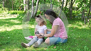 Young Woman with Daughter Petting Kitten in Park