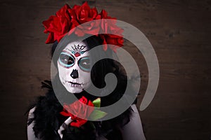 Day of the dead. Halloween. Young woman in day of the dead mask skull face art and rose. Dark background.