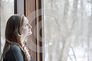 Young woman day dreaming and looking out window photo