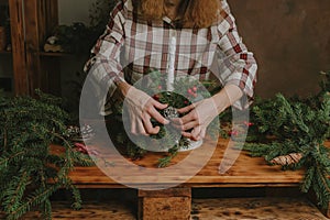 Young woman decorating Christmas flower arrangement.