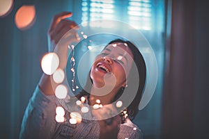 Young woman decorating home with LED fairy lights