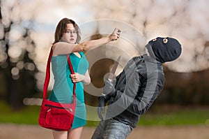 Young woman is defending with pepper spray against armed thief.