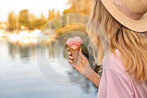 Young woman with delicious ice cream in waffle cone outdoors. Space for text