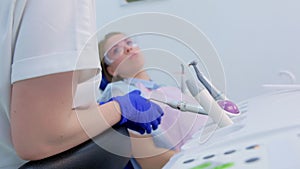 Young woman in dental chair talks about her problem to dentist, side view.