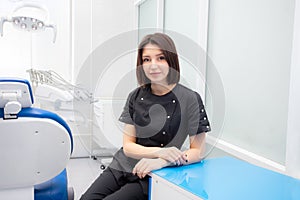 a young woman dentist is sitting in her medical office in a black suit