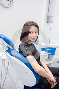 a young woman dentist is sitting in her medical office in a black suit