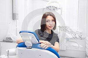 a young woman dentist is sitting in her medical office in a black suit