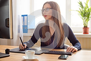 Young woman designer drawing on graphic tablet