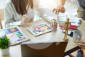 Young woman designer working with tablet color samples for selection on office desk