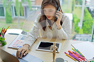 Young woman designer working with tablet color samples for selection on office desk,