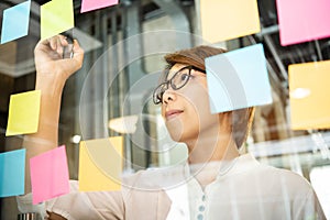 Young woman designer writing new ideas at sticky notes