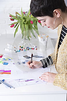 young woman designing fashion dresses drawing with colored pencils
