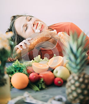 Young woman on a diet succumbed to temptation and passionately bites a white crispy long loaf