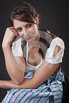 Young woman in a dirndl sitting thinking