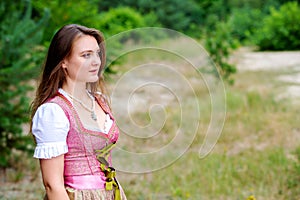 Young woman in dirndl standing outdoors in meadow