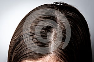 Young woman with dirty greasy hair on gray background