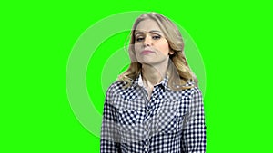 Young woman with distrustful look on green screen.