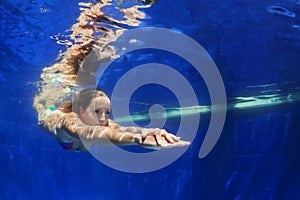 Young woman dive underwater in blue swimming pool