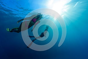 A young woman is diving with a buddy